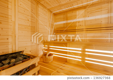 Interior of a traditional wood sauna room featuring a bucket and heated stones Interior of a traditional wood sauna room featuring a bucket and heated stones 136927368