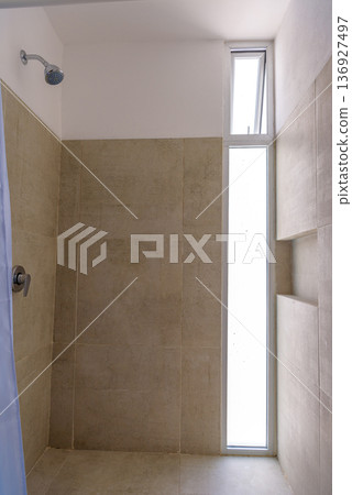 Bright walk-in shower with window and beige tiles Bright walk-in shower with window and beige tiles 136927497