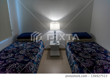 Twin bedroom with illuminated bedside lamp at night 136927513