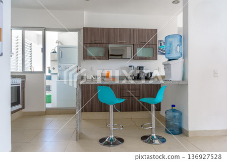 Modern kitchen with breakfast bar and turquoise bar stools 136927528
