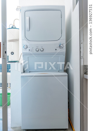 Stackable washer and dryer combo unit in white laundry area Stackable washer and dryer combo unit in white laundry area 136927531