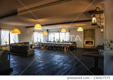 Spacious banquet hall with fireplace and large dining table Spacious banquet hall with fireplace and large dining table 136927575