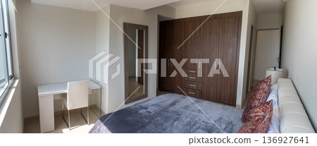 Modern bedroom interior with desk and large wardrobe 136927641