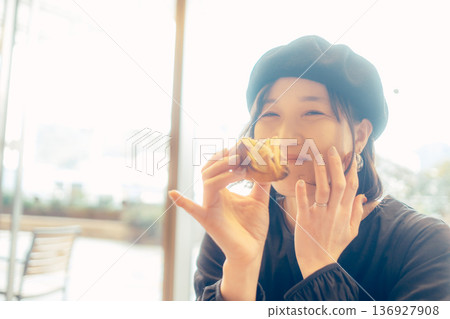 Japanese woman eating bread at a cafe 136927908