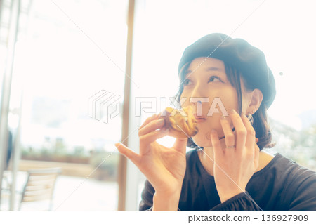 Japanese woman eating bread at a cafe Japanese woman eating bread at a cafe 136927909