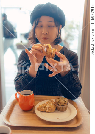Japanese woman eating bread at a cafe Japanese woman eating bread at a cafe 136927913