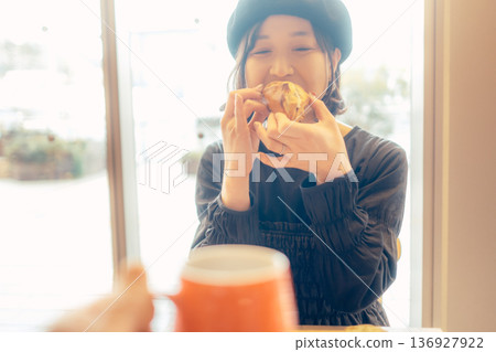 Japanese woman eating bread at a cafe 136927922