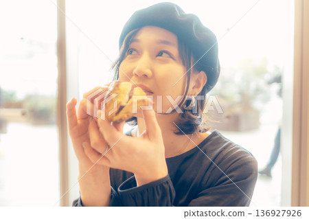 Japanese woman eating bread at a cafe Japanese woman eating bread at a cafe 136927926