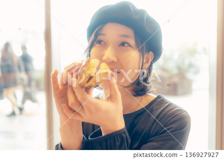 Japanese woman eating bread at a cafe Japanese woman eating bread at a cafe 136927927