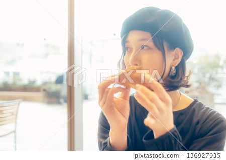 Japanese woman eating bread at a cafe 136927935