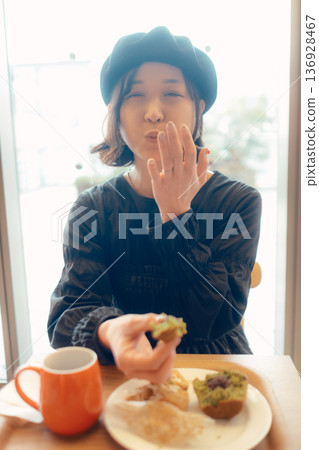 Japanese woman eating bread at a cafe 136928467