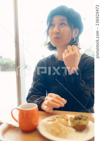 Japanese woman eating bread at a cafe 136928472