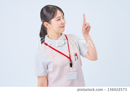 A woman in a white coat posing with her fingers raised A woman in a white coat posing with her fingers raised 136928573