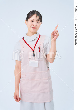 A woman in a white coat posing with her fingers raised 136928576