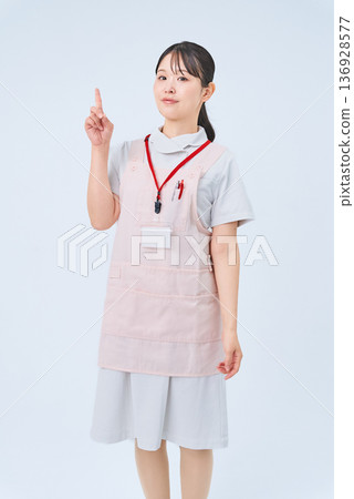 A woman in a white coat posing with her fingers raised A woman in a white coat posing with her fingers raised 136928577