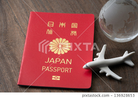 A red Japanese passport with a miniature airplane and the Earth A red Japanese passport with a miniature airplane and the Earth 136928653