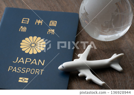 A blue Japanese passport with a miniature airplane and globe 136928944