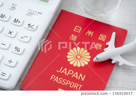A red Japanese passport and a calculator with a miniature of an airplane and the Earth A red Japanese passport and a calculator with a miniature of an airplane and the Earth 136929037