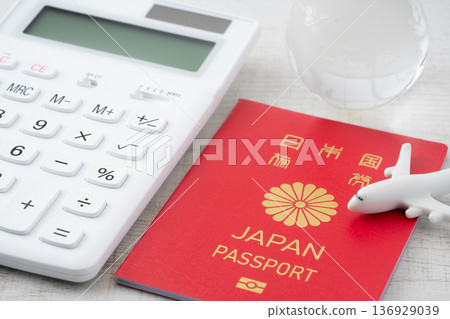 A red Japanese passport and a calculator with a miniature of an airplane and the Earth A red Japanese passport and a calculator with a miniature of an airplane and the Earth 136929039