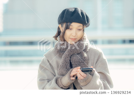一位女士在冬日的城市使用智慧型手機 一位女士在冬日的城市使用智慧型手機 136929234