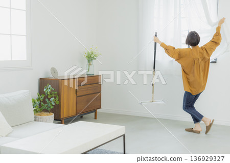 A woman looking in the mirror in the living room A woman looking in the mirror in the living room 136929327