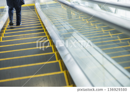 Businessman riding escalator 136929380