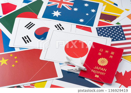 A red Japanese passport and a miniature airplane against a background of many flag cards 136929419