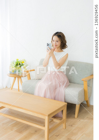 一個微笑的女人看著智能手機 136929456