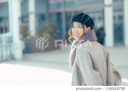 一位女子漫步在冬日的城市中,回頭望去。 一位女子漫步在冬日的城市中,回頭望去。 136929756