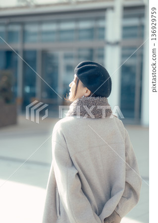 一位女子漫步在冬日的城市中,回頭望去。 一位女子漫步在冬日的城市中,回頭望去。 136929759