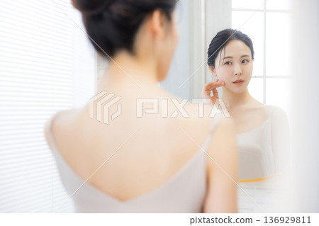 Young woman looking in the mirror in the bathroom Young woman looking in the mirror in the bathroom 136929811