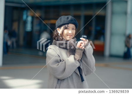 A woman checking her smartphone while waiting outdoors in winter A woman checking her smartphone while waiting outdoors in winter 136929839