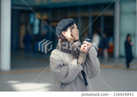 A woman checking her smartphone while waiting outdoors in winter A woman checking her smartphone while waiting outdoors in winter 136929841