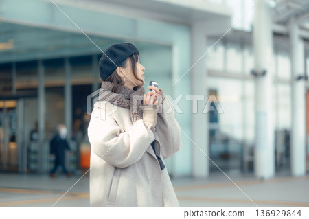 A woman checking her smartphone while waiting outdoors in winter A woman checking her smartphone while waiting outdoors in winter 136929844