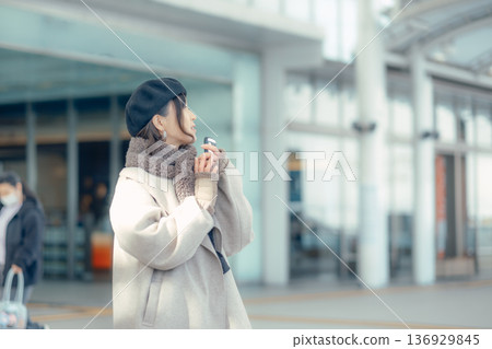 A woman checking her smartphone while waiting outdoors in winter A woman checking her smartphone while waiting outdoors in winter 136929845