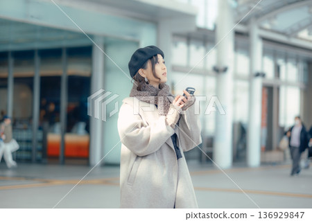 冬天，一位女士在戶外等候時正在查看智慧型手機。 136929847