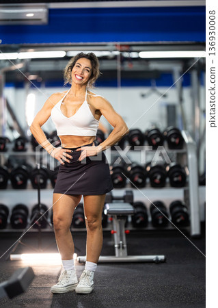Fit woman smiling in gym showing health and confidence Fit woman smiling in gym showing health and confidence 136930008