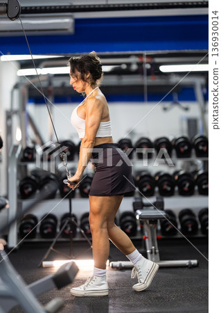 Fit woman training triceps on cable machine in gym Fit woman training triceps on cable machine in gym 136930014