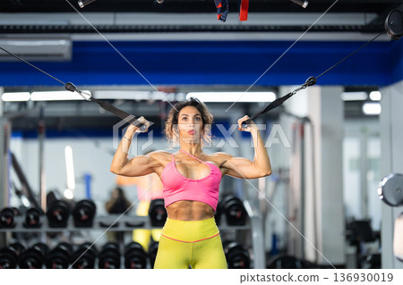 Athletic woman training bicep muscles at gym achieving fitness goals Athletic woman training bicep muscles at gym achieving fitness goals 136930019