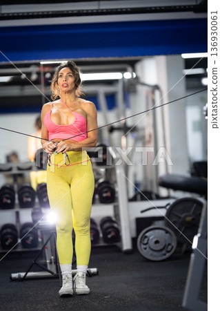 Woman exercising arms with cable machine in gym 136930061