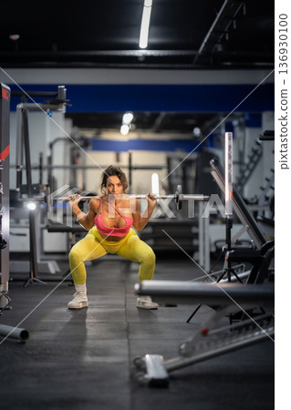Fit woman training legs with barbell squatting in gym Fit woman training legs with barbell squatting in gym 136930100