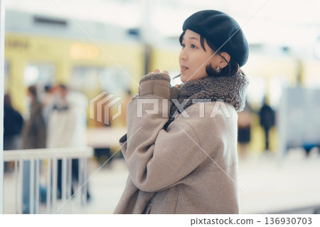 一位三十多歲的女子一邊喝咖啡一邊在車站內行走。 一位三十多歲的女子一邊喝咖啡一邊在車站內行走。 136930703