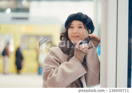 一位三十多歲的女子一邊喝咖啡一邊在車站內行走。 一位三十多歲的女子一邊喝咖啡一邊在車站內行走。 136930711