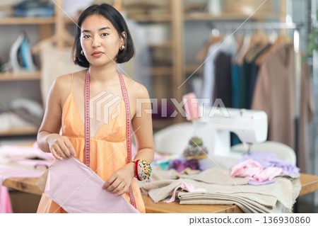 Young woman seamstress with pattern in sewing workshop Young woman seamstress with pattern in sewing workshop 136930860