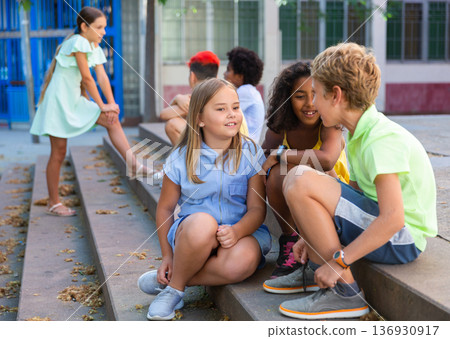 Group of kids sitting on stairs outdoors and talking Group of kids sitting on stairs outdoors and talking 136930917