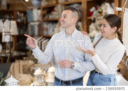 Positive young married couple choosing new garden furniture in furniture store 136930935