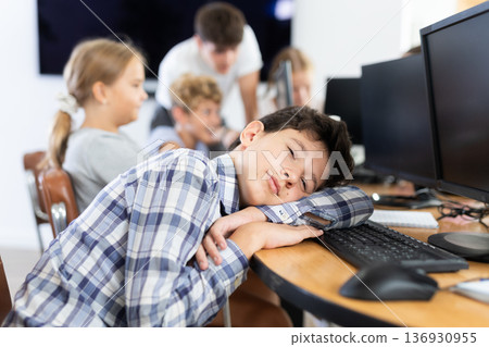 Tired male schoolgirl fell asleep on computer keyboard in class 136930955