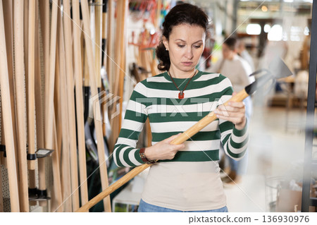 Adult woman choosing hoe in store Adult woman choosing hoe in store 136930976