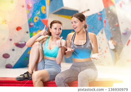 Rest after rock climbing - two friends exchange impressions about training at climbing wall Rest after rock climbing - two friends exchange impressions about training at climbing wall 136930979