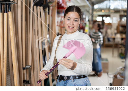 Young woman choosing shovel in store Young woman choosing shovel in store 136931022